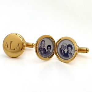Könnte beinhalten: Goldene Manschettenknöpfe mit einem Foto-Medaillon und einem gravierten Monogramm "ALA".