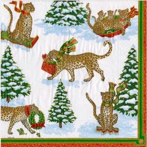May include: A white paper napkin with a festive Christmas design. The napkin features illustrations of leopards with holiday scarves and gifts, set against a snowy backdrop with Christmas trees. The border is red and green.