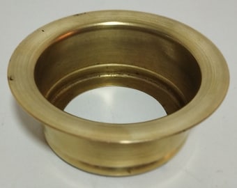 May include: A brass sink strainer with a round, slightly raised rim. The strainer is designed to fit over a drain opening in a sink.
