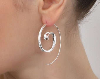 May include: A silver hoop earring featuring a continuous spiral design that curves inwards towards the centre. The earring is constructed from a smooth, polished metal wire that forms a circular shape with an open, tapering end.