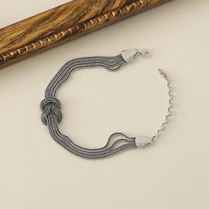 Puede incluir: Pulsera de plata con un dise&ntilde;o anudado y m&uacute;ltiples cadenas.