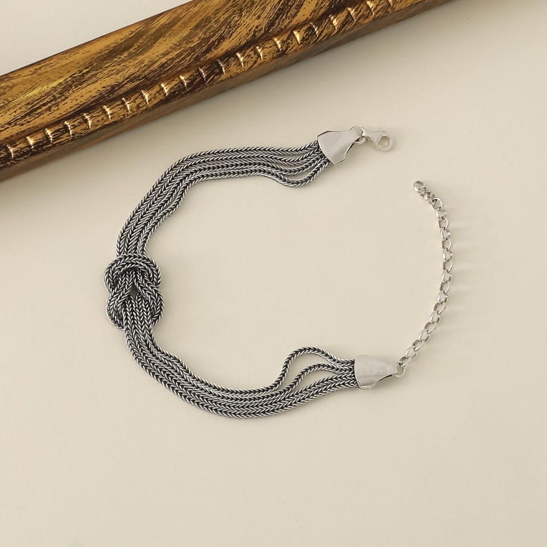 Puede incluir: Pulsera de plata con un dise&ntilde;o anudado y m&uacute;ltiples cadenas.