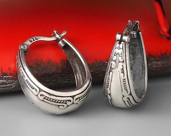 May include: A pair of silver hoop earrings featuring an oxidized finish and intricate embossed scrollwork patterns. The inner band of one earring is clearly stamped with the number 925, indicating sterling silver composition.