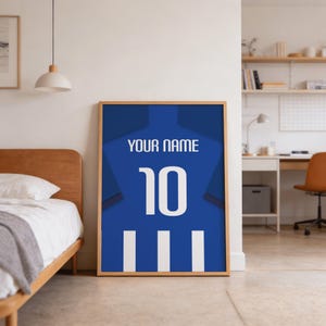 A framed poster with a blue background and white text, displaying the number 10, is standing on a floor in a bedroom.