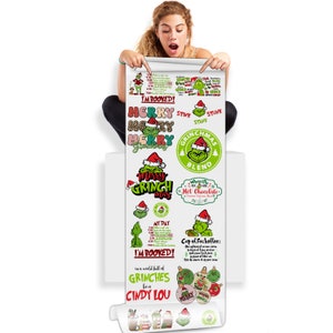 May include: A white roll of stickers featuring Grinch-themed designs. The stickers include text such as "Merry Grinchmas", "Grinchmas Blend", and "Cup of Fuckoffee". The stickers are green, red, and white.
