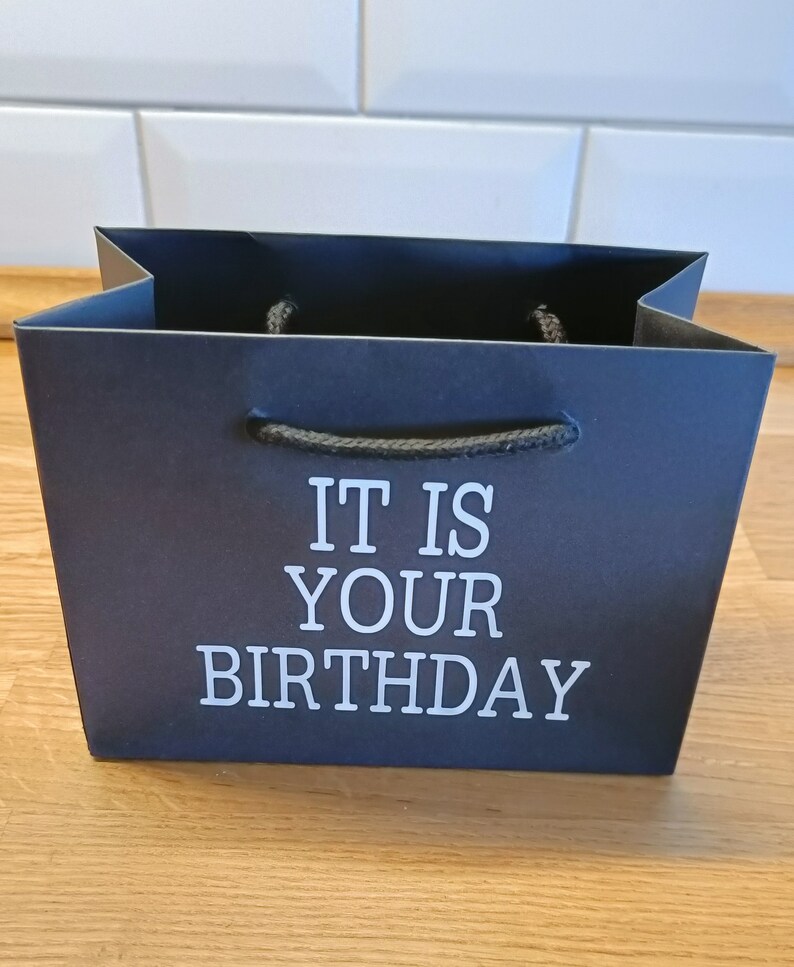May include: Black gift bag with white text that reads "It is your birthday".