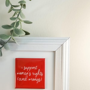 May include: Red square magnet with white text that reads "I support women's rights (and wrongs)"