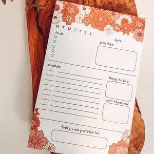May include: A printable daily planner with a floral border. The planner includes sections for to-do lists, schedules, priorities, things to buy, and a gratitude journal.