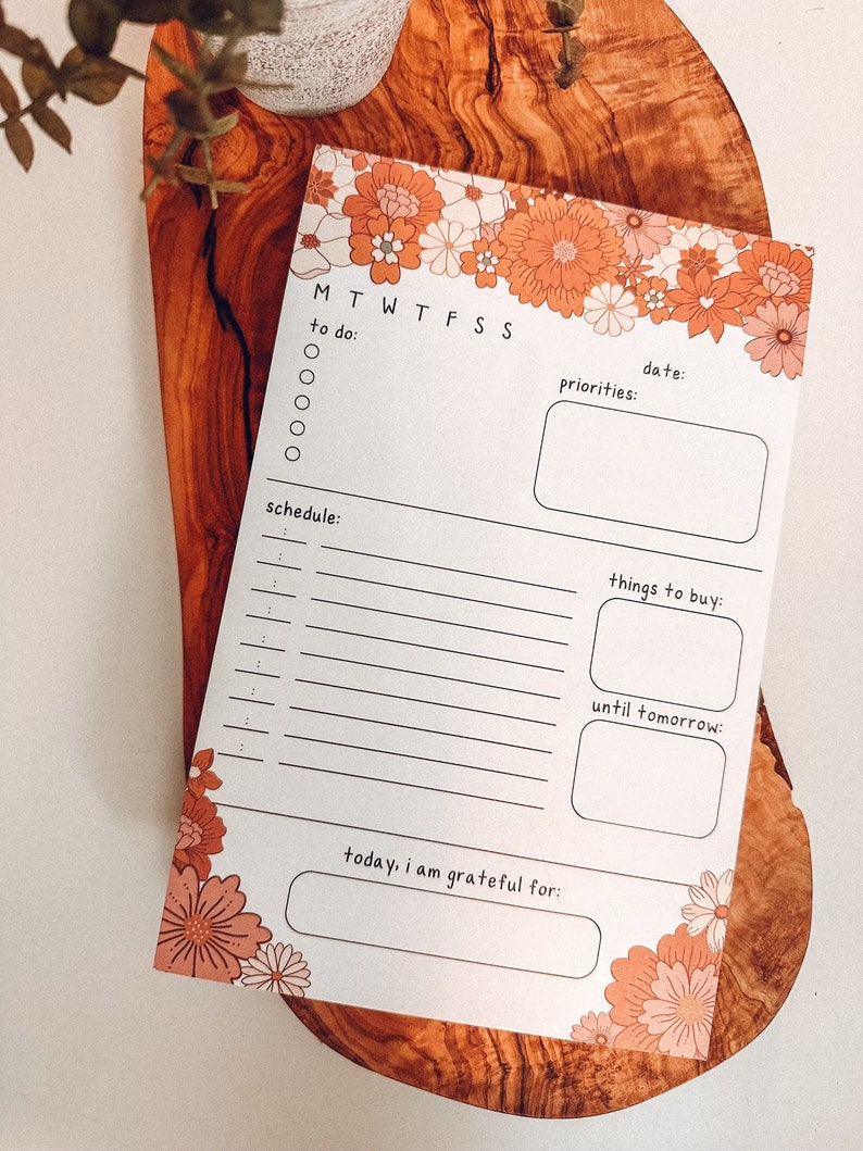 May include: A printable daily planner with a floral border. The planner includes sections for to-do lists, schedules, priorities, things to buy, and a gratitude journal.
