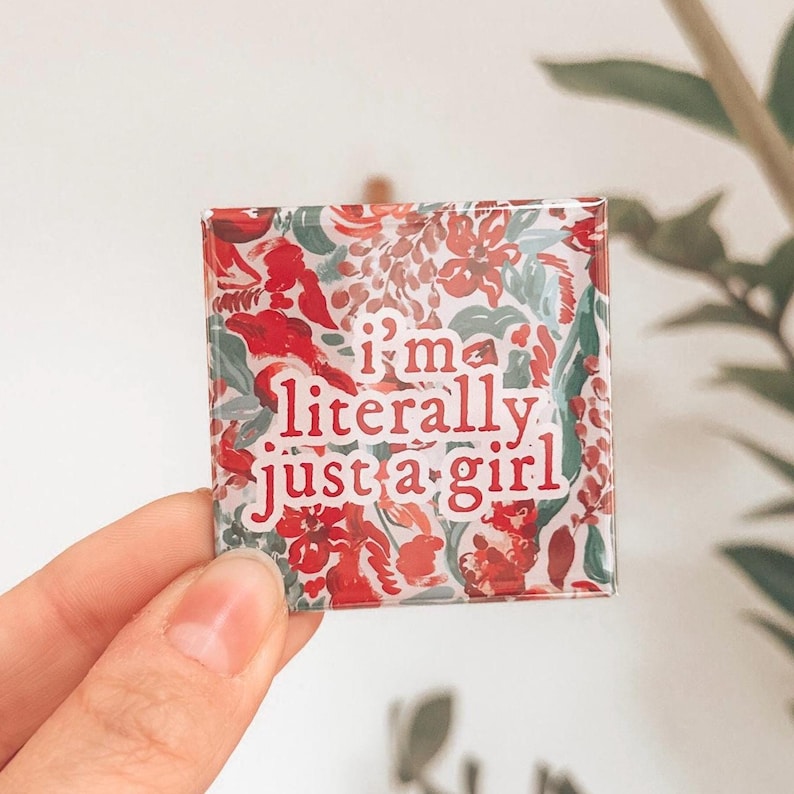 K&ouml;nnte beinhalten: Ein quadratischer Glasmagnet mit einem Blumenmuster in Rot-, Gr&uuml;n- und Wei&szlig;t&ouml;nen. Der Text "i'm literally just a girl" ist in Rot auf dem Magneten gedruckt.