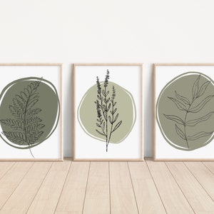 K&ouml;nnte beinhalten: Set aus drei minimalistischen Kunstdrucken mit Strichzeichnungen verschiedener Pflanzen in gr&uuml;nen Kreisen auf wei&szlig;em Hintergrund. Die Drucke sind in naturfarbenen Holzrahmen gerahmt.