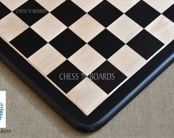 May include: A black and white chessboard with a black border. The board is made of wood and has a smooth finish. The squares are all the same size and are arranged in a checkerboard pattern. The board is labeled "Chess 'N Boards" in the upper right corner.