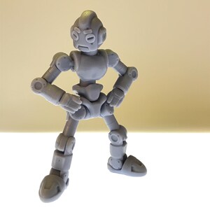 Puede incluir: Una figura de robot articulada gris con una expresi&oacute;n severa. La figura est&aacute; posada con los brazos doblados por los codos y las manos en las caderas, y las piernas separadas. El robot tiene una cabeza redondeada, un cuerpo segmentado y articulaciones visibles.