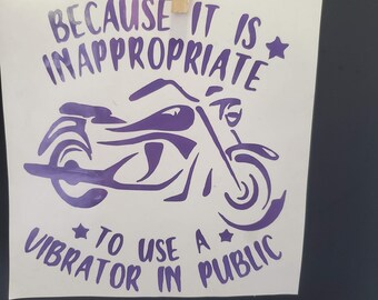 May include: A white square decal featuring a purple graphic of a motorcycle in the center. The text reads: BECAUSE IT IS INAPPROPRIATE TO USE A VIBRATOR IN PUBLIC. The decal is held by a wooden clothespin at the top edge against a black background.