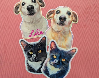 May include: Three pet portraits, two dogs and one cat, printed on white sticker paper. The dogs are both white with brown markings and have their heads tilted up. The cat is black and white with yellow eyes. The dog on the left has the name "Lola" written in pink below it.