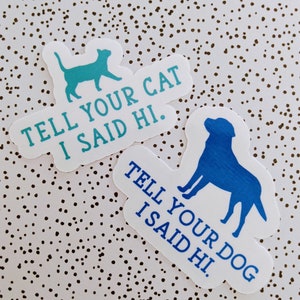 May include: Two stickers with blue silhouettes of a cat and a dog. The stickers have white text that reads "Tell your cat I said hi." and "Tell your dog I said hi."