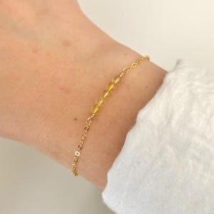 May include: A gold chain bracelet with small, clear yellow beads.