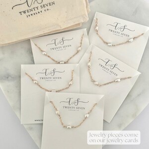 May include: Five white cards with gold chains and pearls on them. Each card has the text "T&S TWENTY SEVEN JEWELRY CO." printed on it. The cards are on a white surface. Jewelry pieces come on our jewelry cards.