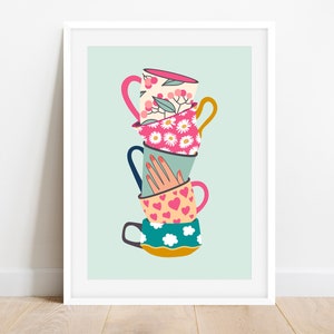 May include: A framed art print featuring a stack of colorful teacups. Each cup has a unique design, including floral patterns, daisies, hearts, and clouds. A hand with red nails is placed in the middle of the stack. The background is a light teal color.