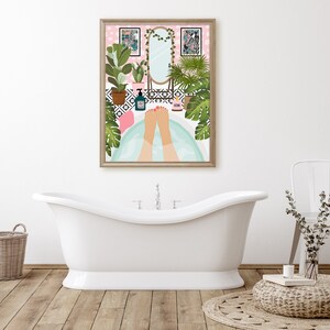 May include: A framed art print depicts a relaxing bathroom scene. The artwork shows a person's feet in a bathtub, surrounded by plants, a mirror, and decorative items. The color palette includes pink, green, and white, creating a calming atmosphere.