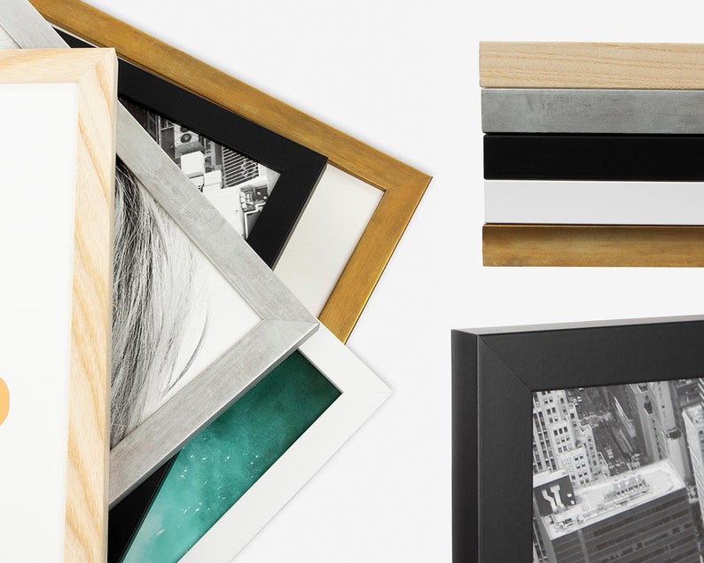 May include: A variety of picture frames in different colors and styles, including natural wood, silver, black, and gold. The frames are stacked on top of each other, with the top frame being a natural wood frame.