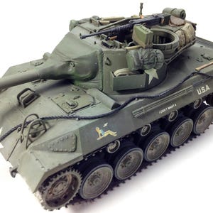 May include: An olive drab model tank with a long barrel and multiple details, including a machine gun, storage packs, and the text "U.S.A." and "I DON'T WANT A". The tank has a white star and a pin-up girl graphic.