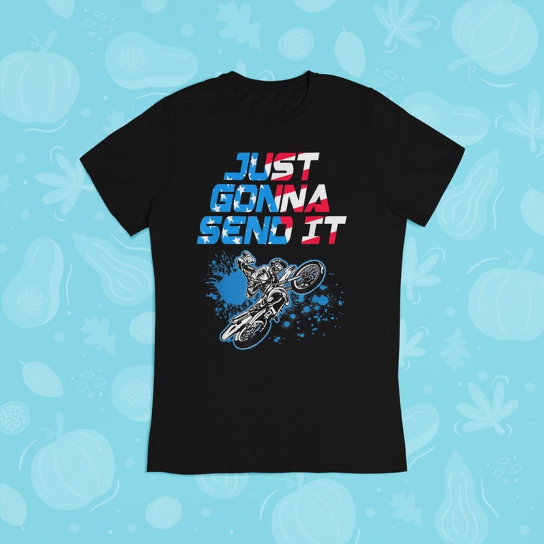 Puede incluir: Camiseta negra con un gr&aacute;fico de un piloto de motocross saltando sobre una rampa. El gr&aacute;fico es en azul, rojo y blanco, y el texto "JUST GONNA SEND IT" est&aacute; impreso sobre el gr&aacute;fico.