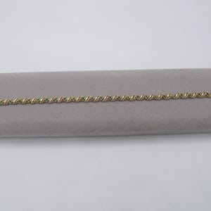 May include: A gold bracelet with green gemstones set in a twisted design.