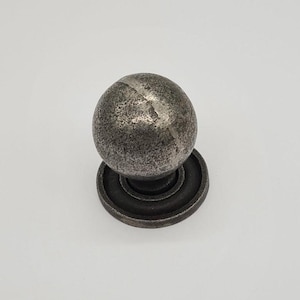 May include: A silver metal cabinet knob with a round, textured ball and a circular base.