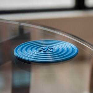 May include: A blue silicone coaster with a concentric circle design and the Japanese character for "water" in the centre.