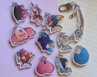 May include: A set of ten colorful acrylic keychains featuring various cartoon characters. The keychains are shaped like fish, hearts, and other whimsical designs.
