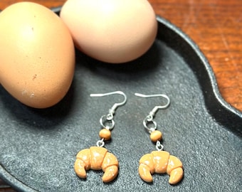 Adorables pendientes colgantes en miniatura con forma de croissant de desayuno.