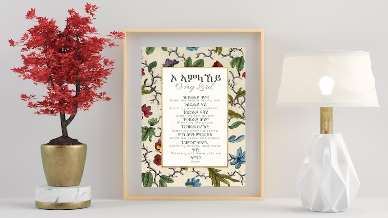 Pode incluir: Uma impress&atilde;o emoldurada com elementos florais e bot&acirc;nicos, com texto em uma fonte de script. A impress&atilde;o est&aacute; em uma moldura dourada, e uma pequena &aacute;rvore vermelha em um vaso dourado est&aacute; &agrave; esquerda. Uma l&acirc;mpada branca com base dourada est&aacute; &agrave; direita.