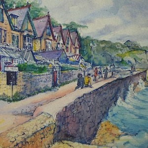 May include: A watercolor painting of a row of houses along a stone wall overlooking a blue ocean with white waves crashing against the rocks. The houses are painted in shades of yellow, green, and purple. There are people walking along the wall.