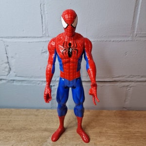 Pu&ograve; includere: Una action figure rossa e blu di Spider-Man con un simbolo di ragno nero sul petto. La figura ha una maschera bianca con occhi neri.