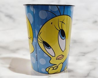 Può includere: Un bicchiere di plastica blu e giallo con un'immagine di cartone animato di Tweety Bird. Il bicchiere ha un motivo a pois bianchi.