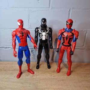 Pu&ograve; includere: Tre action figure di personaggi di Spider-Man. Una &egrave; rossa e blu, una &egrave; nera e bianca e una &egrave; rossa con accenti neri.
