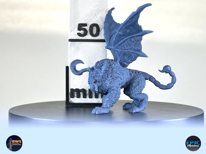 May include: A blue plastic miniature of a winged lion with a scorpion tail. The miniature is about 5 cm tall and is standing on a gray circular base.