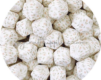 May include: A close-up of a group of white silicone beads with a floral pattern. The beads are hexagonal in shape and have a hole in the centre. The beads are perfect for making necklaces, bracelets, and other jewellery.