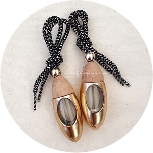 May include: Two gold car air fresheners with wooden tops and black and white string hangers.