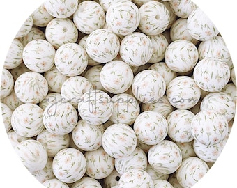 May include: A close-up of a large quantity of white silicone beads with a delicate floral pattern in shades of pink and green.