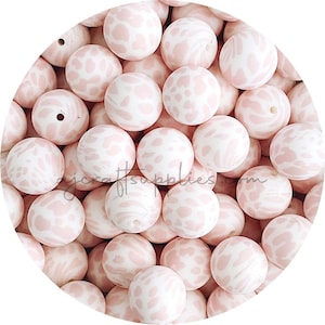 以下が含まれることがあります： ヒョウ柄のピンクと白のシリコンビーズのグループのクローズアップ。ビーズは丸く、表面が滑らかです。