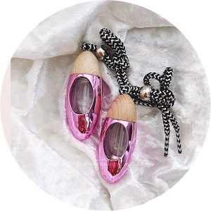 May include: Two pink car air fresheners with a wood top and a clear glass bottle. The fresheners are hanging from a black and white string.