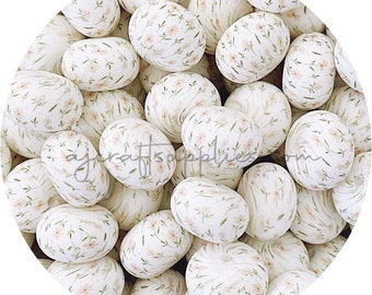 May include: A close-up of a group of white ceramic eggs with a delicate floral pattern in shades of pink and green. The eggs are arranged in a circular pattern, creating a visually appealing and decorative display.