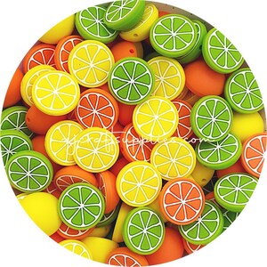 May include: A collection of colourful silicone fruit slice beads in yellow, orange, and green. The beads are shaped like lemon, lime, and orange slices.