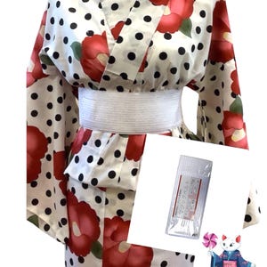 Puede incluir: Yukata de lunares blancos y negros con flores de camelia rojas. El yukata tiene una faja blanca. La imagen tambi&eacute;n incluye un paquete de mascarillas faciales con texto japon&eacute;s.