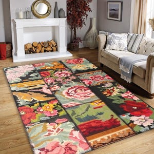 Op de afbeelding: Een kleurrijk patchwork tapijt met bloemenmotieven in tinten roze, rood, groen en geel op een zwarte achtergrond.