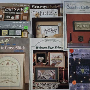 May include: A collection of cross-stitch and embroidery pattern books. Titles include "Short and Sweet," "Short and Sassy #2," "Say It in Cross-Stitch," and "Welcome Dear Friend." The books feature various designs and sayings for home decor.