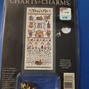 May include: A cross-stitch pattern featuring a beehive, flowers, and a birdhouse. The pattern includes an alphabet and numbers for personalization. The pattern is 8 inches by 18 inches and comes with a charm.