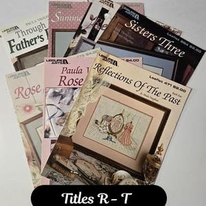 May include: A collection of Leisure Arts cross-stitch pattern leaflets including titles such as Reflections Of The Past, Sisters Three, Rose, and Through Father's Eyes. Each booklet features printed cover art displaying finished embroidery designs.